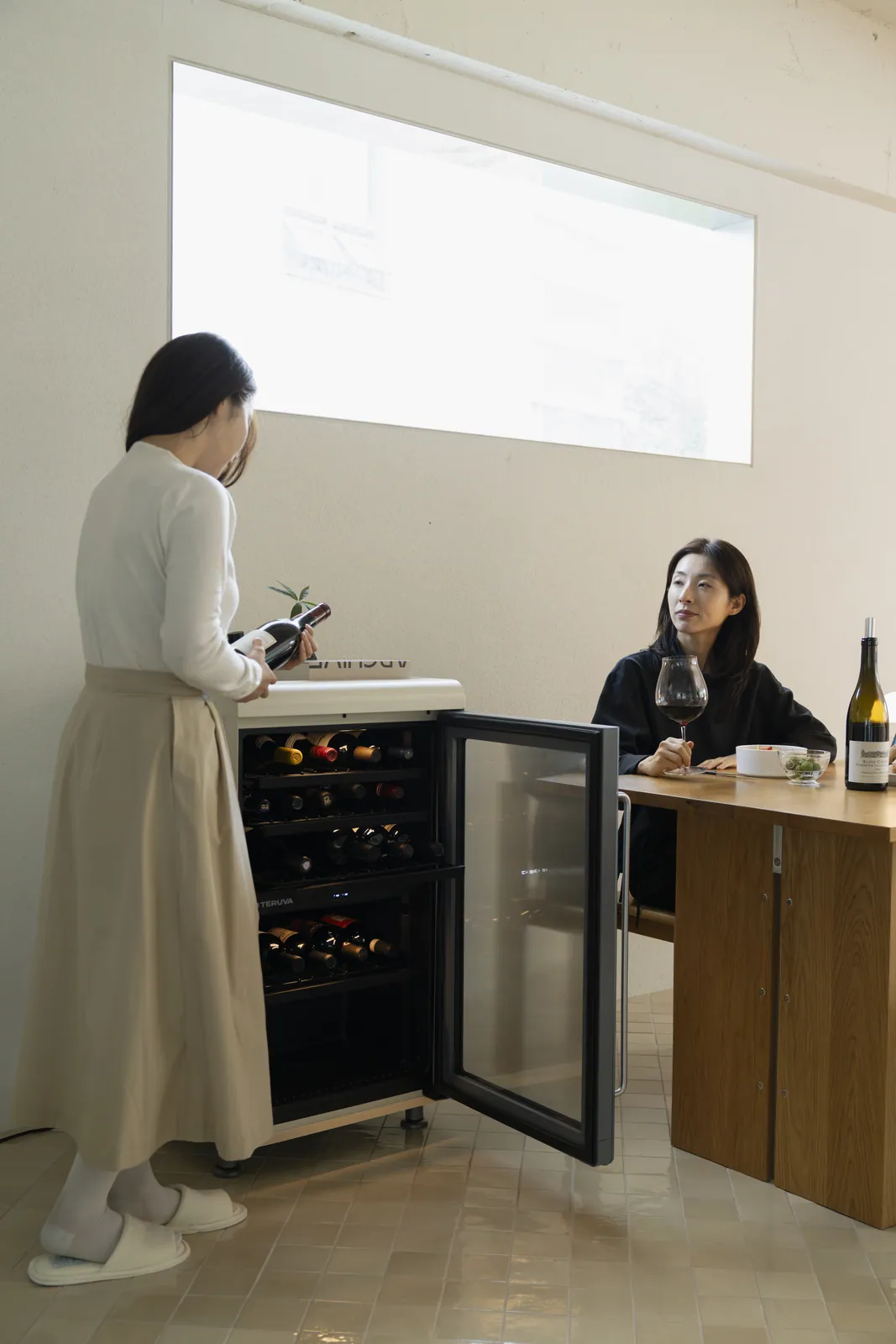 식탁 옆 와인셀러에서 와인을 고르는 모습